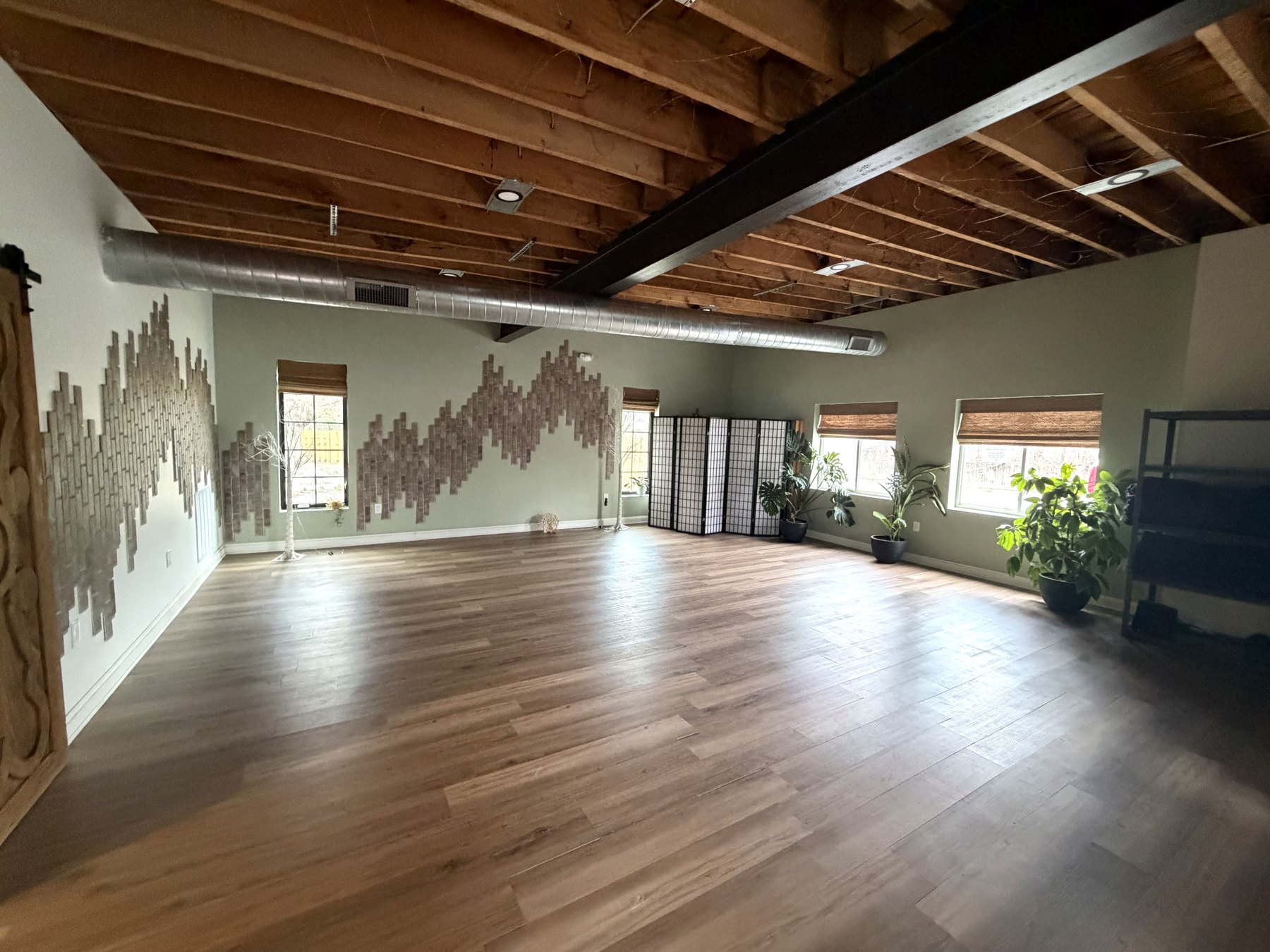 Open studio room with wood floors and natural light at Indigo Sun